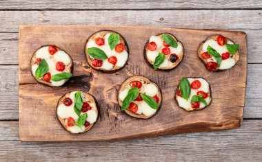 İtalyan mini pizzası. Patlıcan peynirli ve fesleğenli. Kırsal arkaplan üstü görünümünde