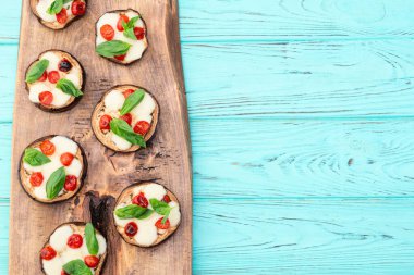 İtalyan mini pizzası. Patlıcan peynirli ve fesleğenli. Kırsal arkaplan üstü görünümünde