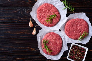 Ahşap zemin üzerinde sığır eti hamburgeri için çiğ pirzola. Üst görünüm