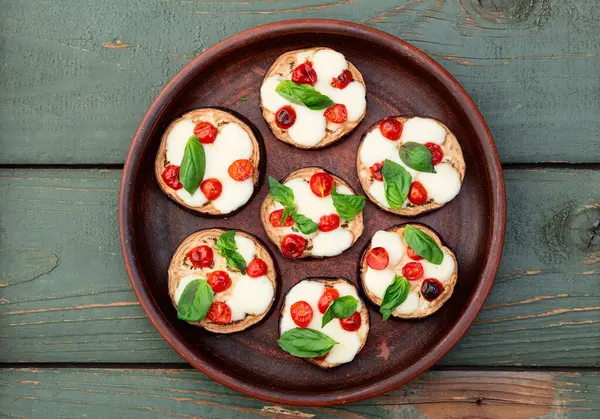 İtalyan mini pizzası. Patlıcan peynirli ve fesleğenli. Kırsal arkaplan üstü görünümünde