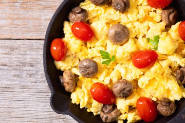 Sağlıklı vejetaryen kahvaltısı. Tavada yumurta, kiraz domatesli ve maydanozlu. Üst görünüm