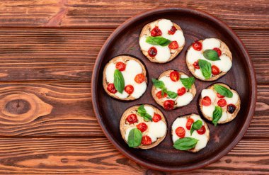 İtalyan mini pizzası. Patlıcan peynirli ve fesleğenli. Kırsal arkaplan üstü görünümünde