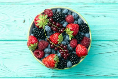 Kase fotoğrafında olgun renkli böğürtlenlerin karışımı. Yabanmersini, çilek, ahududu, böğürtlen ve frenk üzümü. Kırsal arkaplanda üst görünüm