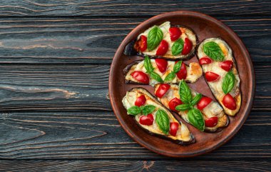 İtalyan mini pizzası. Patlıcan peynirli ve fesleğenli. Kırsal arkaplan üstü görünümünde