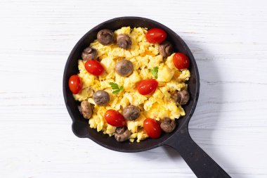 Sağlıklı vejetaryen kahvaltısı. Tavada yumurta, kiraz domatesli ve maydanozlu. Üst görünüm