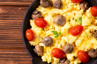 Sağlıklı vejetaryen kahvaltısı. Tavada yumurta, kiraz domatesli ve maydanozlu. Üst görünüm