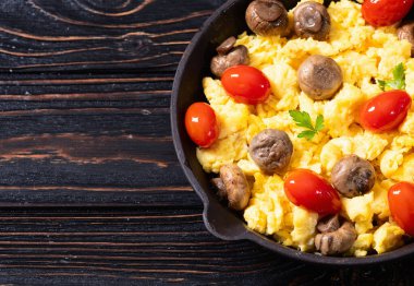 Sağlıklı vejetaryen kahvaltısı. Tavada yumurta, kiraz domatesli ve maydanozlu. Üst görünüm