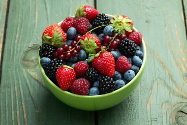 Kase fotoğrafında olgun renkli böğürtlenlerin karışımı. Yabanmersini, çilek, ahududu, böğürtlen ve frenk üzümü. Kırsal arkaplanda üst görünüm