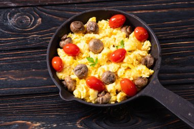 Sağlıklı vejetaryen kahvaltısı. Tavada yumurta, kiraz domatesli ve maydanozlu. Üst görünüm