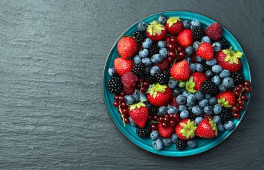 Kase fotoğrafında olgun renkli böğürtlenlerin karışımı. Yabanmersini, çilek, ahududu, böğürtlen ve frenk üzümü. Kırsal arkaplanda üst görünüm