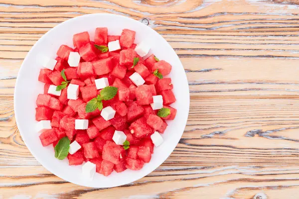 Peynirli ve naneli yaz karpuz salatası. Ahşap arkaplanda üst görünüm