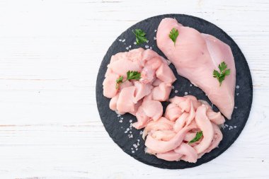 Raw chicken meat fillet ( breast ) Various of cutting in form slice and cube . Top view on rustic background clipart