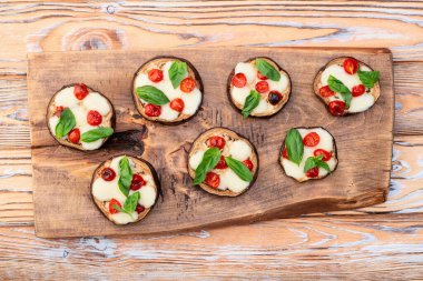 İtalyan mini pizzası. Patlıcan peynirli ve fesleğenli. Kırsal arkaplan üstü görünümünde