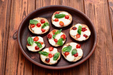 İtalyan mini pizzası. Patlıcan peynirli ve fesleğenli. Kırsal arkaplan üstü görünümünde