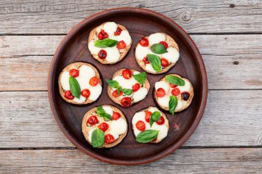 İtalyan mini pizzası. Patlıcan peynirli ve fesleğenli. Kırsal arkaplan üstü görünümünde