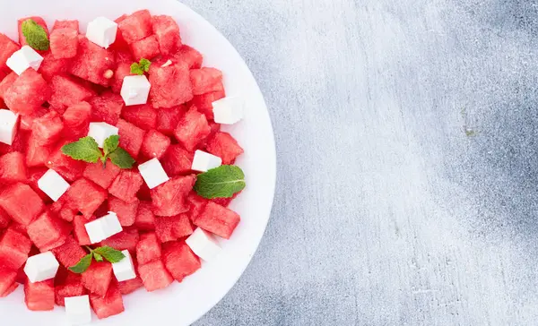 Peynirli ve naneli yaz karpuz salatası. Ahşap arkaplanda üst görünüm