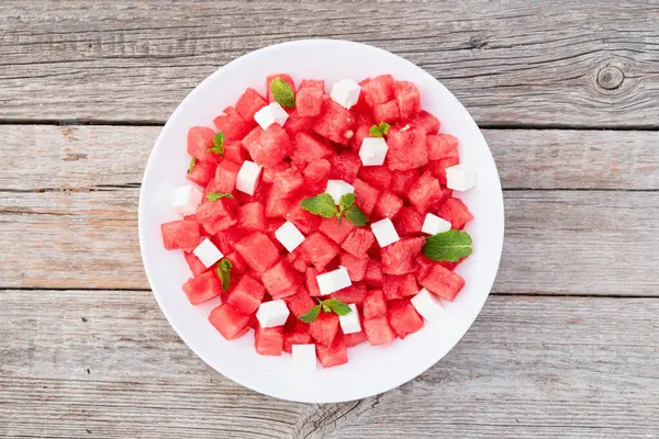 Peynirli ve naneli yaz karpuz salatası. Ahşap arkaplanda üst görünüm