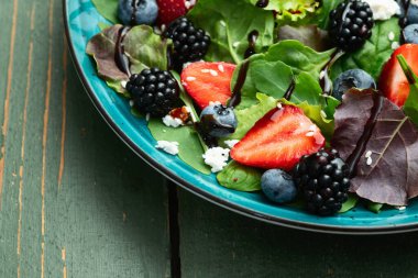 Peynirli feta ve balzamik soslu böğürtlen salatası (yaban mersini böğürtlenli böğürtlen). Kırsal arkaplanda üst görünüm