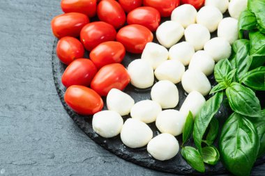 Fesleğen yaprakları, kiraz domatesleri ve mozzarella peyniri. İtalyan bayrağı gibi yiyecek fotoğrafçılığı. Üst görünüm