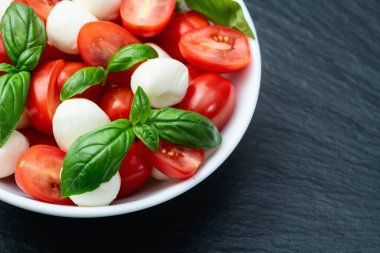 Fesleğen yaprakları, kiraz domatesleri ve mozzarella peyniri. Kase yemek fotoğrafçılığında. Üst görünüm