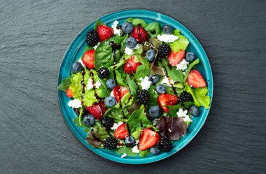 Peynirli feta ve balzamik soslu böğürtlen salatası (yaban mersini böğürtlenli böğürtlen). Kırsal arkaplanda üst görünüm