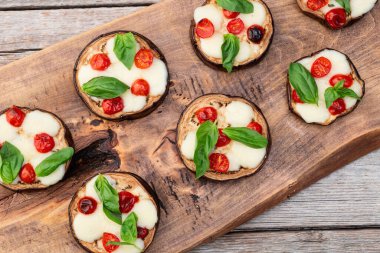 İtalyan mini pizzası. Patlıcan peynirli ve fesleğenli. Kırsal arkaplan üstü görünümünde