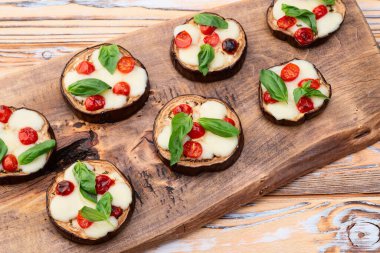 İtalyan mini pizzası. Patlıcan peynirli ve fesleğenli. Kırsal arkaplan üstü görünümünde