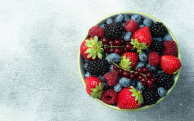 Kase fotoğrafında olgun renkli böğürtlenlerin karışımı. Yabanmersini, çilek, ahududu, böğürtlen ve frenk üzümü. Kırsal arkaplanda üst görünüm