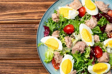 Yumurta ve domates fotoğraflı konserve ton balığı salatası. Kırsal arkaplanda üst görünüm