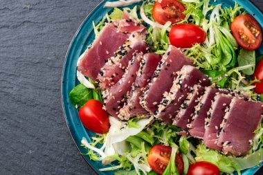 Çiğ ton balığı, susam ve vişneli domates fotoğraflı salata. Kırsal arkaplanda üst görünüm