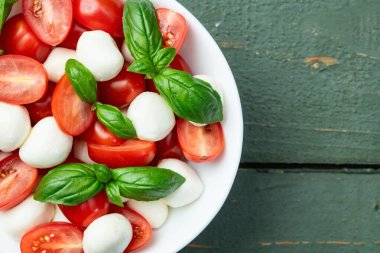 Fesleğen yaprakları, kiraz domatesleri ve mozzarella peyniri. Kase yemek fotoğrafçılığında. Üst görünüm