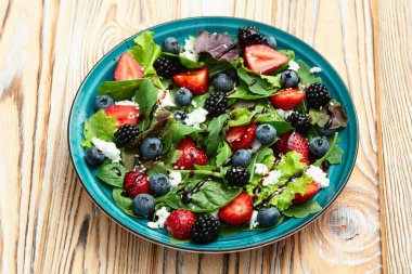 Peynirli feta ve balzamik soslu böğürtlen salatası (yaban mersini böğürtlenli böğürtlen). Kırsal arkaplanda üst görünüm