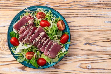 Çiğ ton balığı, susam ve vişneli domates fotoğraflı salata. Kırsal arkaplanda üst görünüm