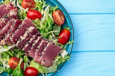 Çiğ ton balığı, susam ve vişneli domates fotoğraflı salata. Kırsal arkaplanda üst görünüm