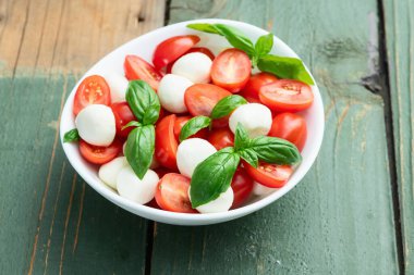 Fesleğen yaprakları, kiraz domatesleri ve mozzarella peyniri. Kase yemek fotoğrafçılığında. Üst görünüm