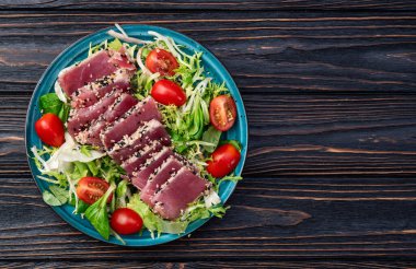 Çiğ ton balığı, susam ve vişneli domates fotoğraflı salata. Kırsal arkaplanda üst görünüm
