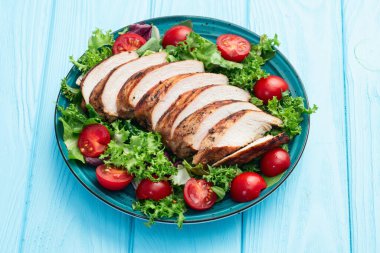 Kızarmış tavuk göğsü (fileto) lahana salatası ve kiraz domatesli. Kırsal arkaplanda üst görünüm