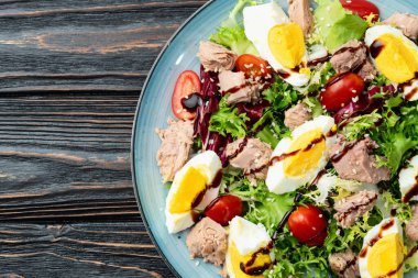 Yumurta ve domates fotoğraflı konserve ton balığı salatası. Kırsal arkaplanda üst görünüm