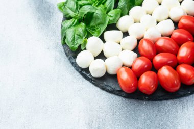 Fesleğen yaprakları, kiraz domatesleri ve mozzarella peyniri. İtalyan bayrağı gibi yiyecek fotoğrafçılığı. Üst görünüm