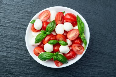 Fesleğen yaprakları, kiraz domatesleri ve mozzarella peyniri. Kase yemek fotoğrafçılığında. Üst görünüm