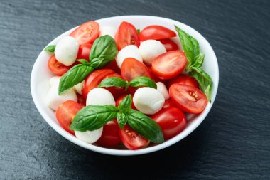 Fesleğen yaprakları, kiraz domatesleri ve mozzarella peyniri. Kase yemek fotoğrafçılığında. Üst görünüm