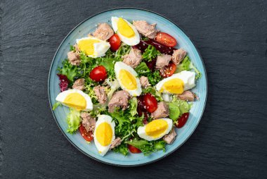 Yumurta ve domates fotoğraflı konserve ton balığı salatası. Kırsal arkaplanda üst görünüm