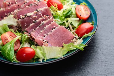 Çiğ ton balığı, susam ve vişneli domates fotoğraflı salata. Kırsal arkaplanda üst görünüm