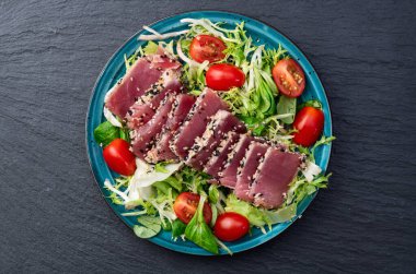 Çiğ ton balığı, susam ve vişneli domates fotoğraflı salata. Kırsal arkaplanda üst görünüm