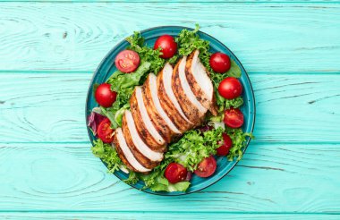 Kızarmış tavuk göğsü (fileto) lahana salatası ve kiraz domatesli. Kırsal arkaplanda üst görünüm