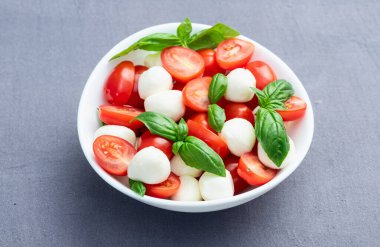 Fesleğen yaprakları, kiraz domatesleri ve mozzarella peyniri. Kase yemek fotoğrafçılığında. Üst görünüm