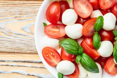 Fesleğen yaprakları, kiraz domatesleri ve mozzarella peyniri. Kase yemek fotoğrafçılığında. Üst görünüm