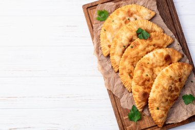 Atıştırmalık çizelgeler. Et fotoğrafçılığı yapan börekler. Kırsal arkaplanda üst görünüm