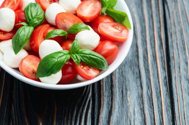 Fesleğen yaprakları, kiraz domatesleri ve mozzarella peyniri. Kase yemek fotoğrafçılığında. Üst görünüm