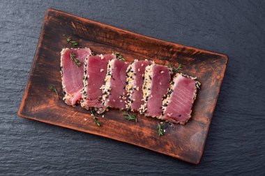 Susamlı dilimlenmiş ton balığı bifteği. Kırsal arkaplanda üst görünüm